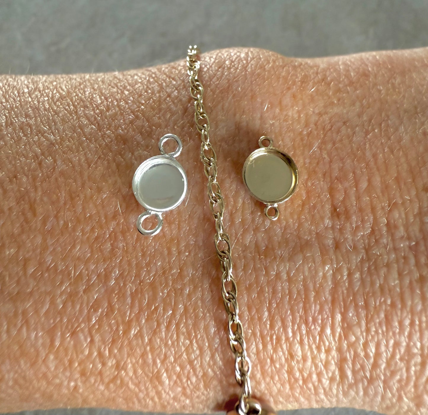 Gold chain with two memorial connectors on a wrist against a neutral background