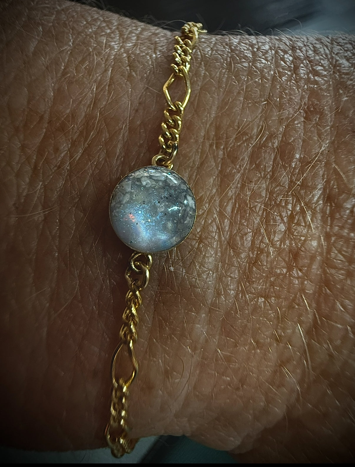 Gold bracelet with a blue gemstone on a wrist
