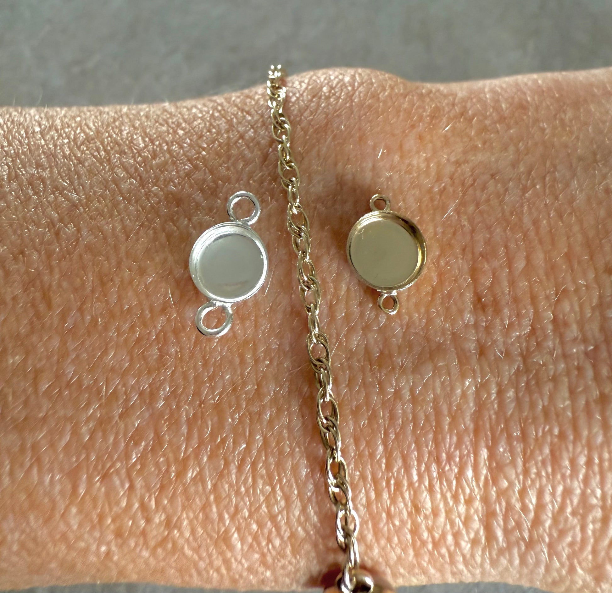 Gold chain with two memorial connectors on a wrist against a neutral background