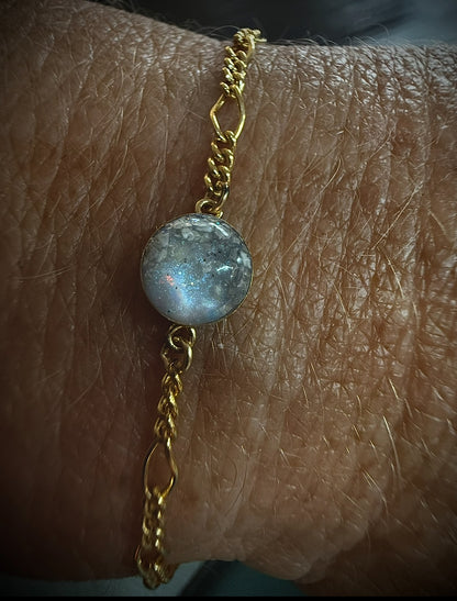 Gold bracelet with a blue gemstone on a wrist